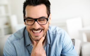 man with glasses smiling and rubbing chin